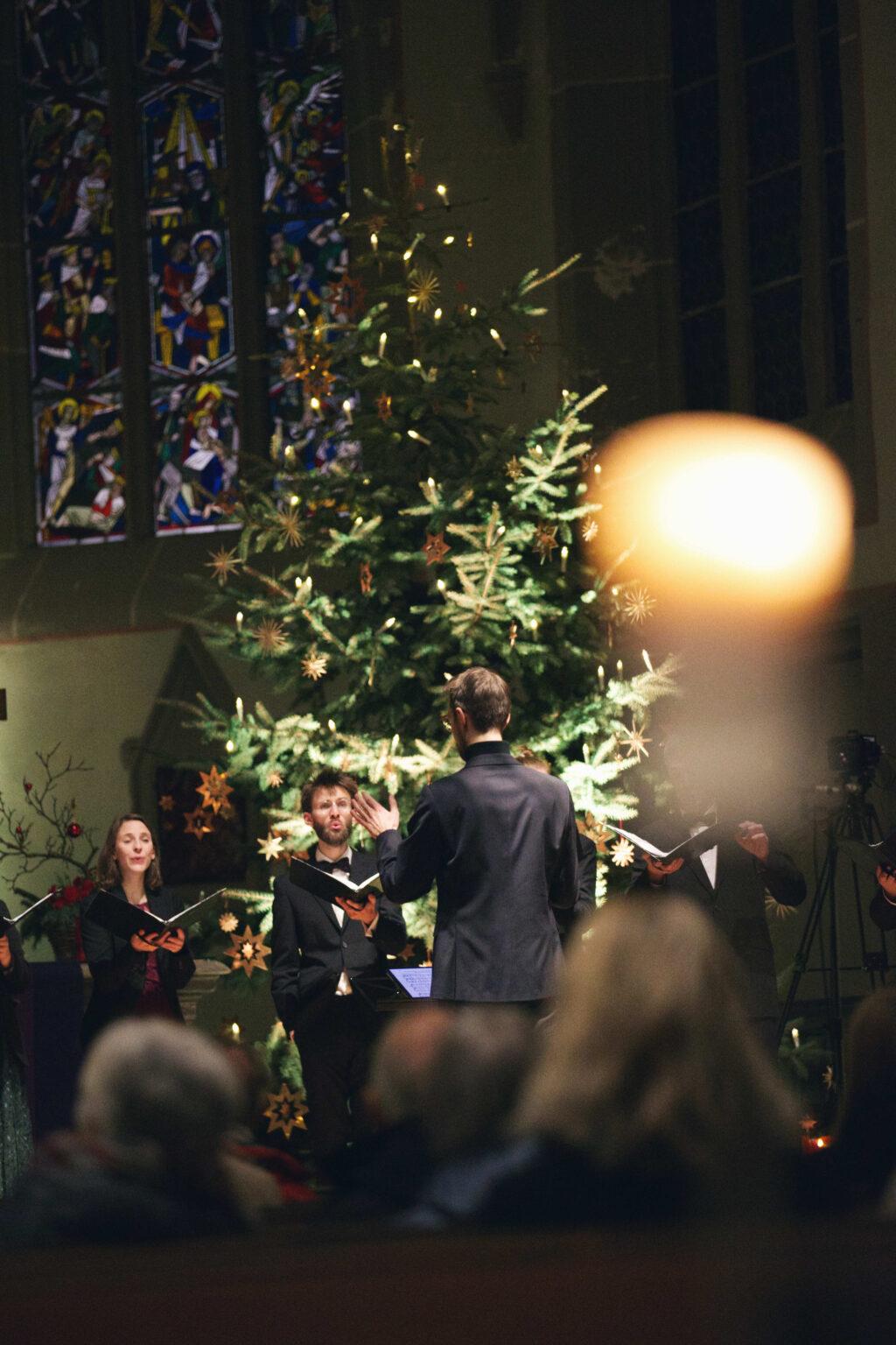 Chor singt vor einem geschmückten Tannenbaum in einer Kirche